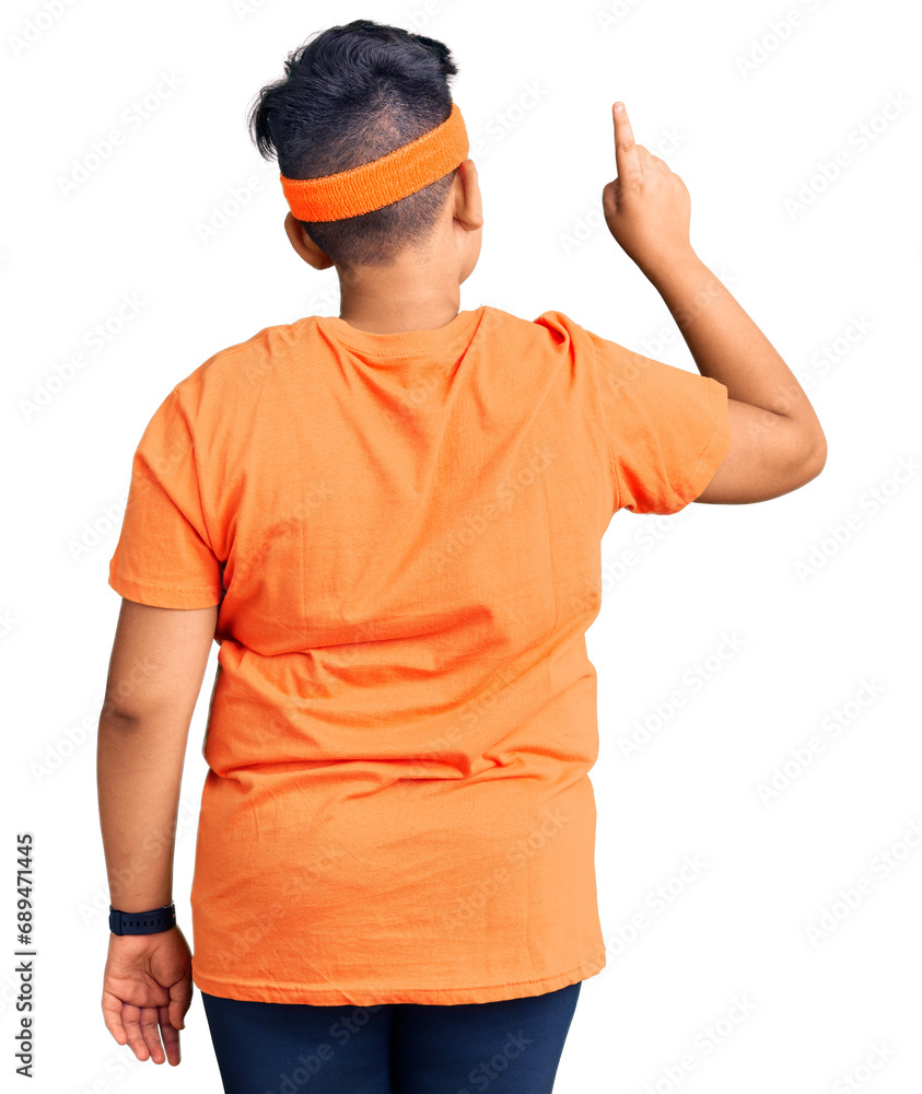 Little boy kid wearing sportswear posing backwards pointing ahead with finger hand Little boy kid wearing sportswear posing backwards pointing ahead with finger hand