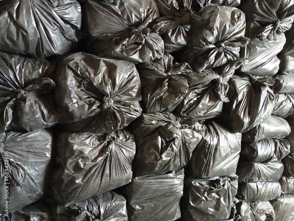 Many filled black garbage bags neatly stacked in a row. Many filled black garbage bags neatly stacked in a row.