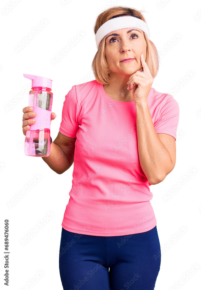 Young blonde woman wearing sportswear holding water bottle serious face thinking about question with hand on chin, thoughtful about confusing idea Young blonde woman wearing sportswear holding water bottle serious face thinking about question with hand on chin, thoughtful about confusing idea