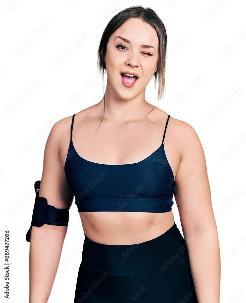 Young hispanic woman wearing sportswear winking looking at the camera with sexy expression, cheerful and happy face. Young hispanic woman wearing sportswear winking looking at the camera with sexy expression, cheerful and happy face.