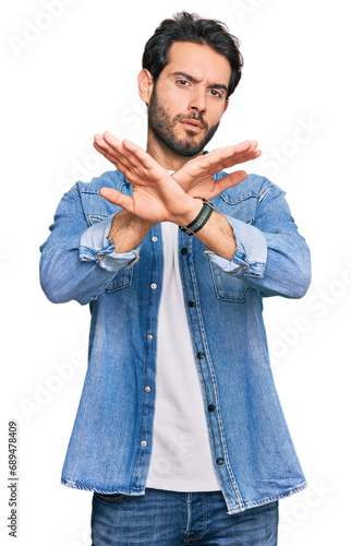 Young hispanic man wearing casual clothes rejection expression crossing arms doing negative sign, angry face