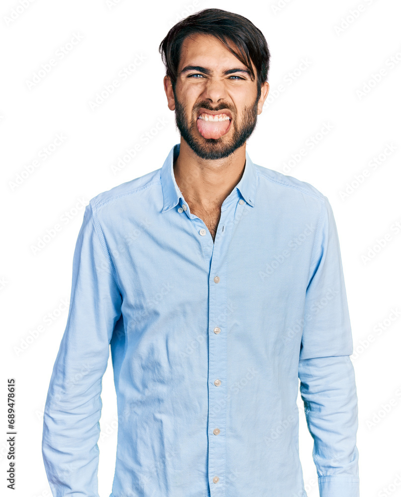 Hispanic man with blue eyes wearing business shirt sticking tongue out happy with funny expression. emotion concept. Hispanic man with blue eyes wearing business shirt sticking tongue out happy with funny expression. emotion concept.