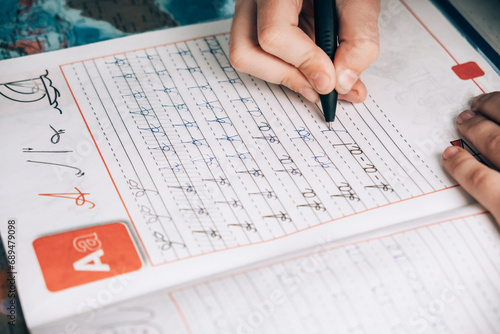 A child uses a pen to practice handwriting the letters of the alphabet in cursive script.