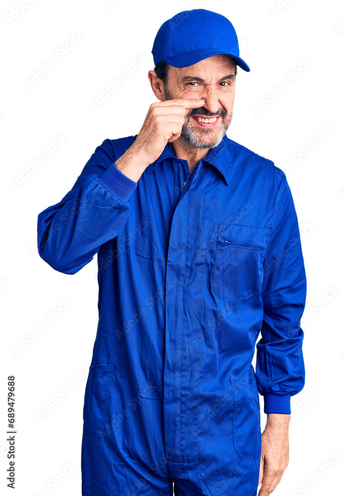 Middle age handsome man wearing mechanic uniform pointing with hand finger to face and nose, smiling cheerful. beauty concept