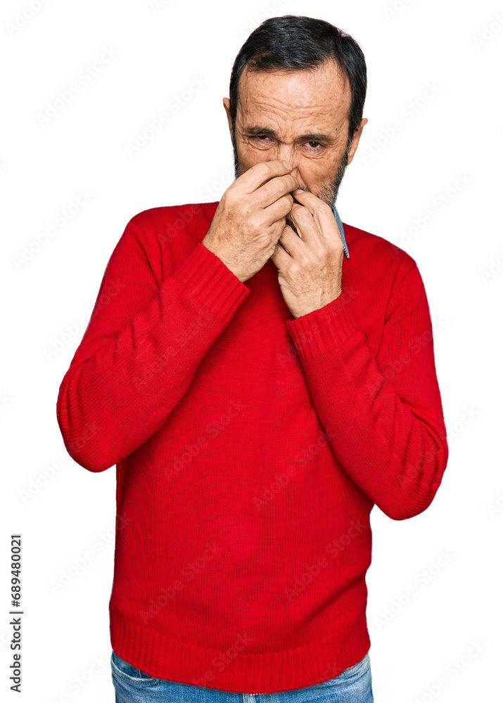Middle age hispanic man wearing casual clothes smelling something stinky and disgusting, intolerable smell, holding breath with fingers on nose. bad smell Middle age hispanic man wearing casual clothes smelling something stinky and disgusting, intolerable smell, holding breath with fingers on nose. bad smell