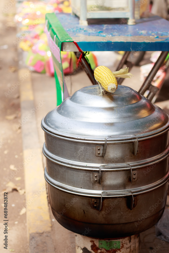 Fototapeta premium Vertical view of a metal steamer for cooking whole corn cob at the sidewalk, a popular khmer streetfood in Kampot, Cambodia
