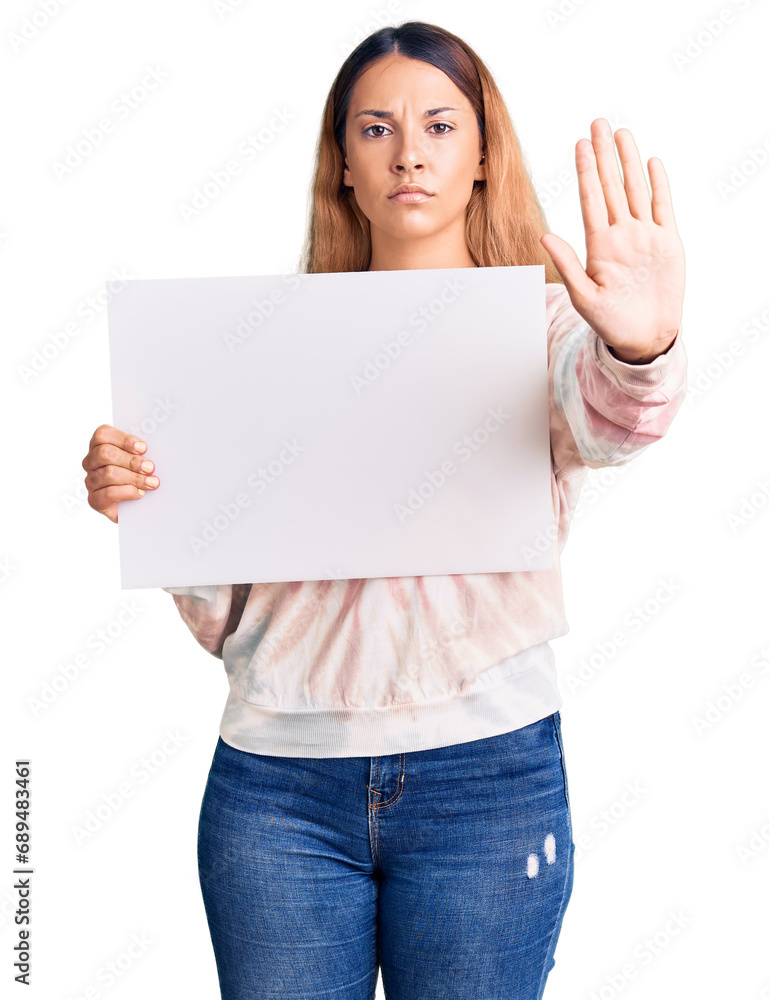 Beautiful young woman holding blank empty banner with open hand doing stop sign with serious and confident expression, defense gesture Beautiful young woman holding blank empty banner with open hand doing stop sign with serious and confident expression, defense gesture