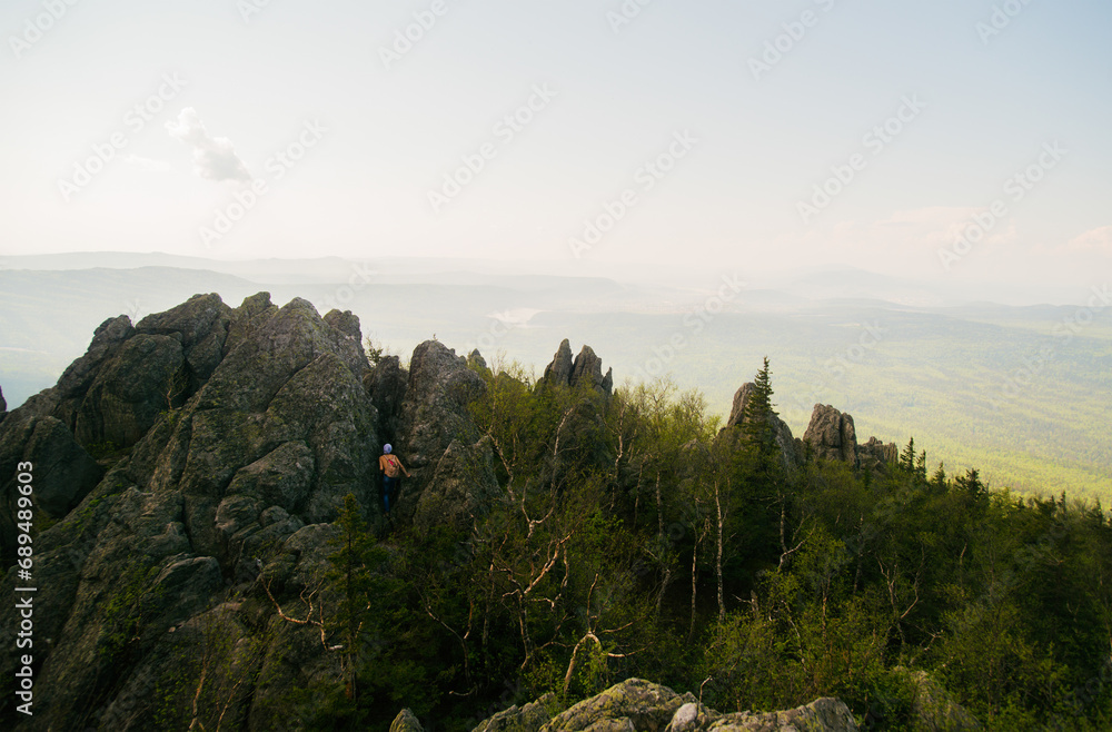 Rear view of teenage male hiker climbing rugged rock formation, Russia