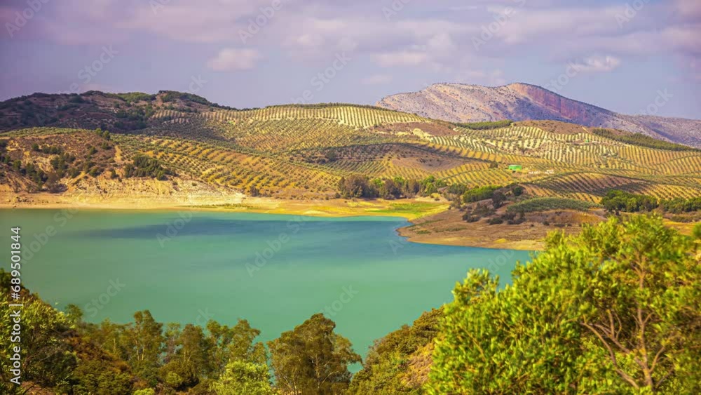 Timelapse shot of cloud movement over El Limonero reservoir, surrounded green countryside along hilly terrain in Malaga, Spain. Timelapse shot of cloud movement over El Limonero reservoir, surrounded green countryside along hilly terrain in Malaga, Spain.