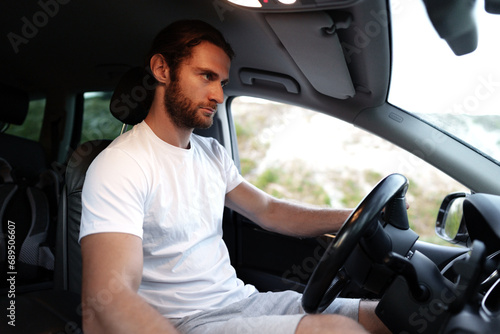 Bearded young man in casual t-shirt drives a car © fotofabrika