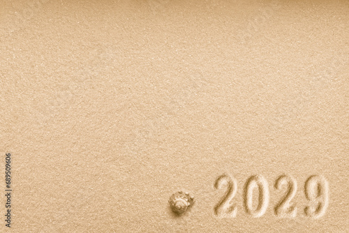 Imprints of numbers 2029 new year and a shell left side on a golden sand