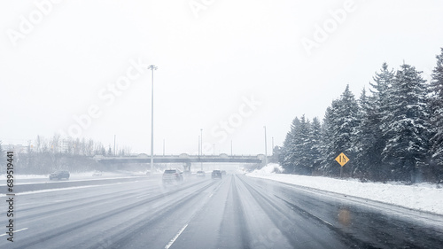 Driving down the highway during a winters storm in Ottawa, Ontario. Road is covered by snow, cars, passing by, fog