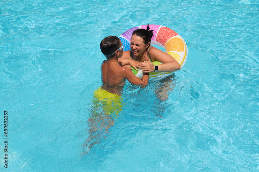 Mother and son play in the pool; a vibrant float between them. Reflects the trend towards quality family leisure time.