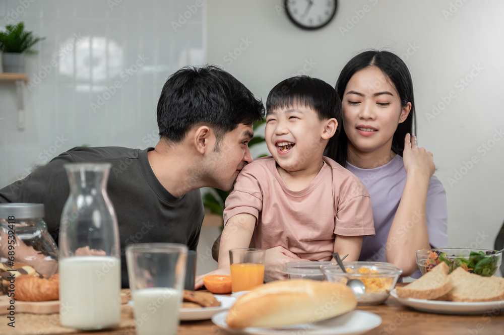 Asian Cute little boy eating vegetable salad with his parents in the kitchen. Lovely Asian family having breakfast together. Happy family activity lifestyle concept. Asian Cute little boy eating vegetable salad with his parents in the kitchen. Lovely Asian family having breakfast together. Happy family activity lifestyle concept.