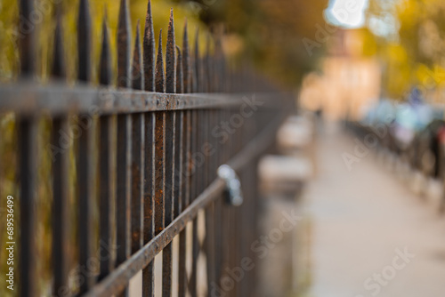 Black metal steel fence in a city. Rustical vintage style fence with spiked tops and rivets visible.