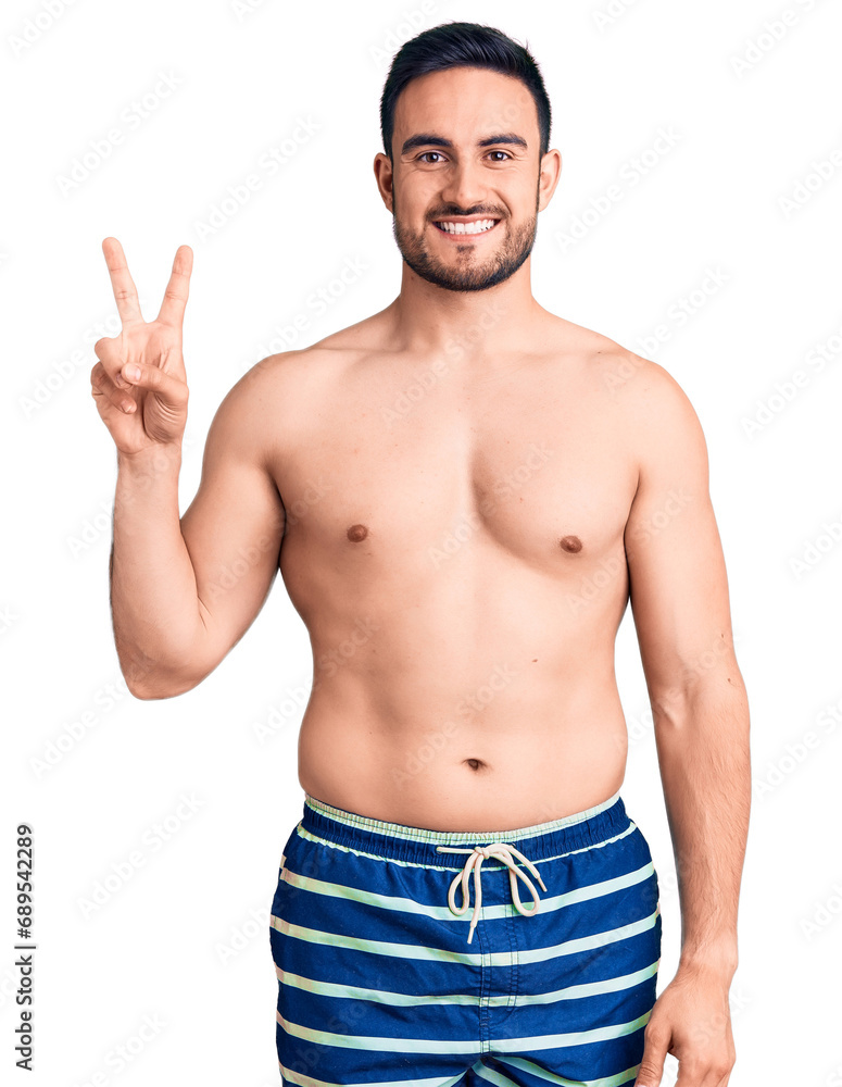 Young handsome man wearing swimwear showing and pointing up with fingers number two while smiling confident and happy. Young handsome man wearing swimwear showing and pointing up with fingers number two while smiling confident and happy.