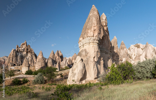 Fairy Chimney and a carved churched in the background in Rose Valley in Cappadocia, Turkey