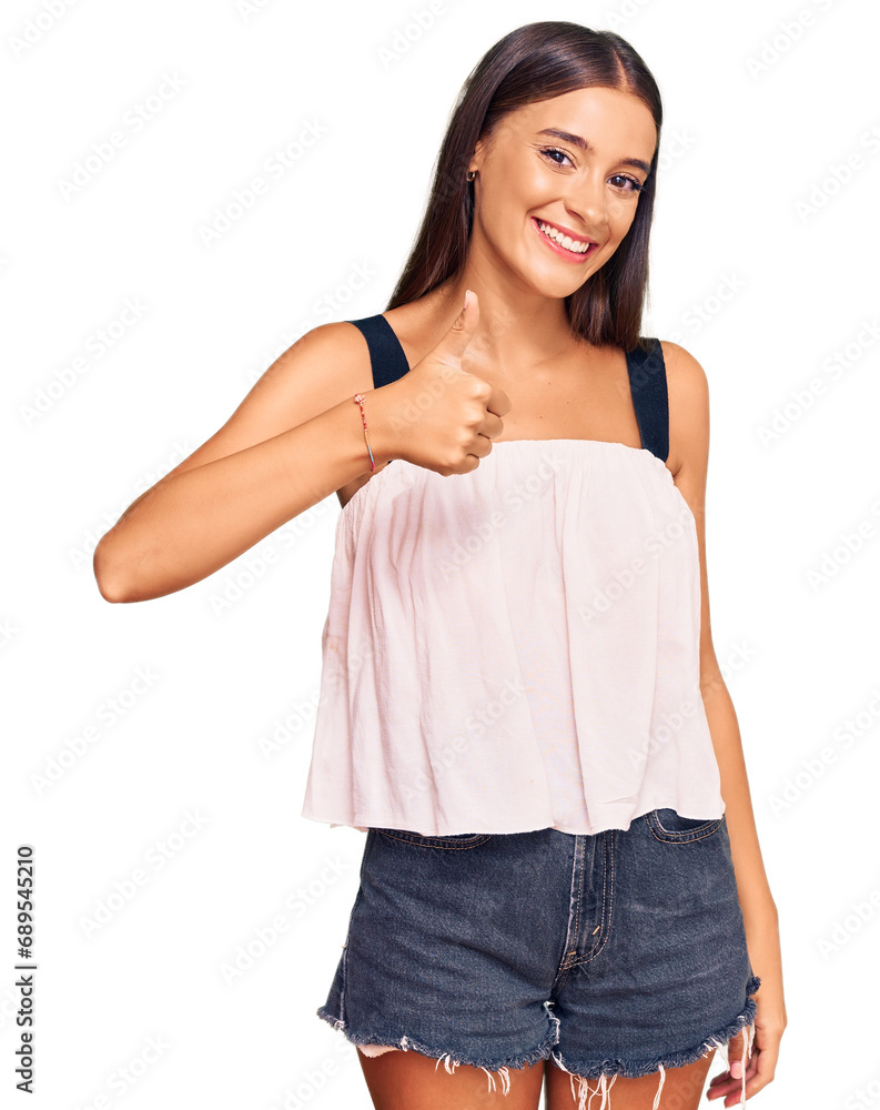 Young hispanic woman wearing casual clothes doing happy thumbs up gesture with hand. approving expression looking at the camera showing success. Young hispanic woman wearing casual clothes doing happy thumbs up gesture with hand. approving expression looking at the camera showing success.