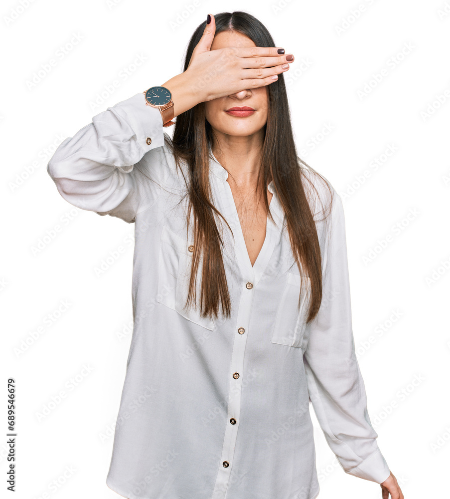 Young beautiful woman wearing casual white shirt covering eyes with hand, looking serious and sad. sightless, hiding and rejection concept Young beautiful woman wearing casual white shirt covering eyes with hand, looking serious and sad. sightless, hiding and rejection concept