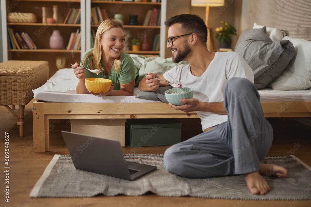 Couple in love enjoying breakfast in bed and using laptop Couple in love enjoying breakfast in bed and using laptop