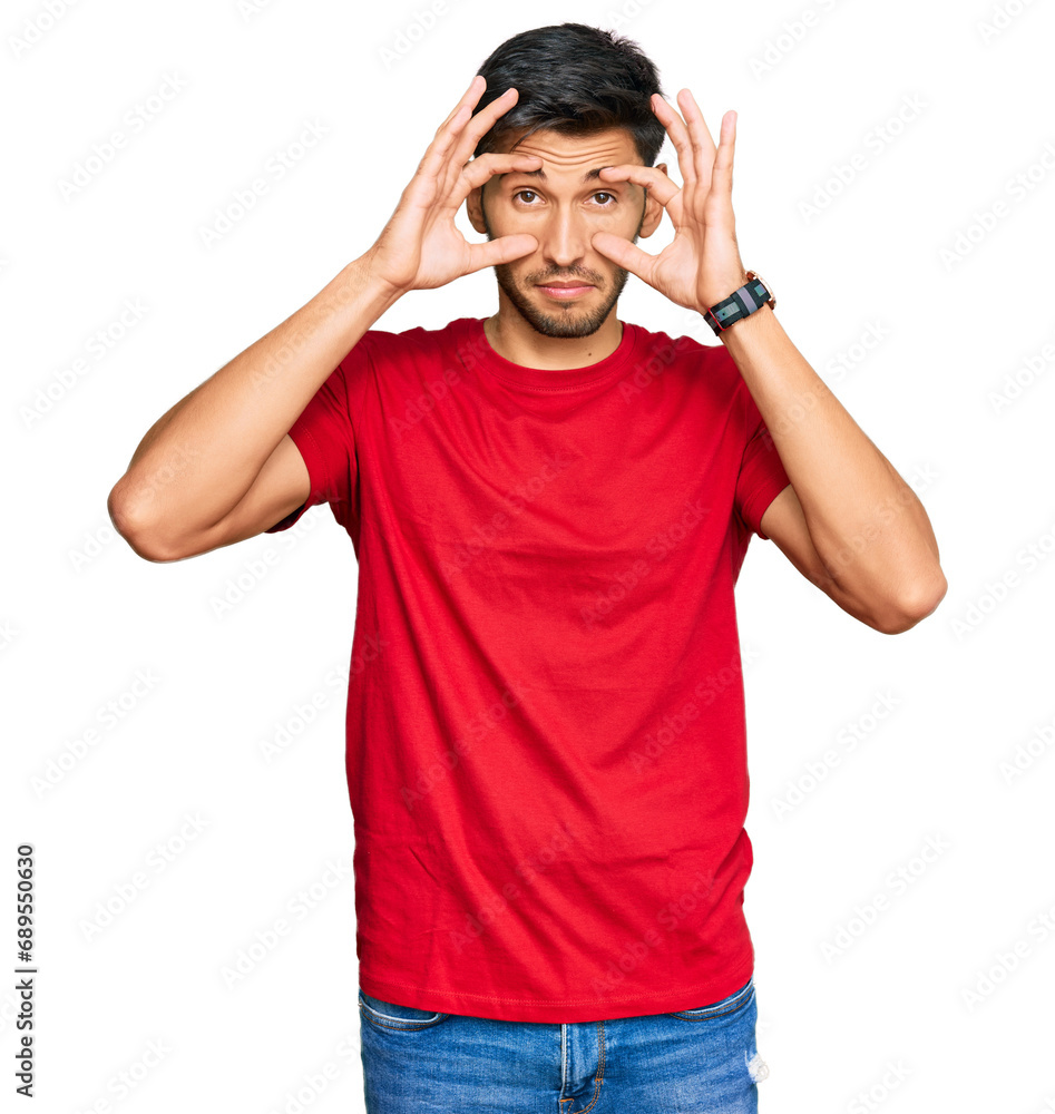 Young handsome man wearing casual red tshirt trying to open eyes with fingers, sleepy and tired for morning fatigue Young handsome man wearing casual red tshirt trying to open eyes with fingers, sleepy and tired for morning fatigue