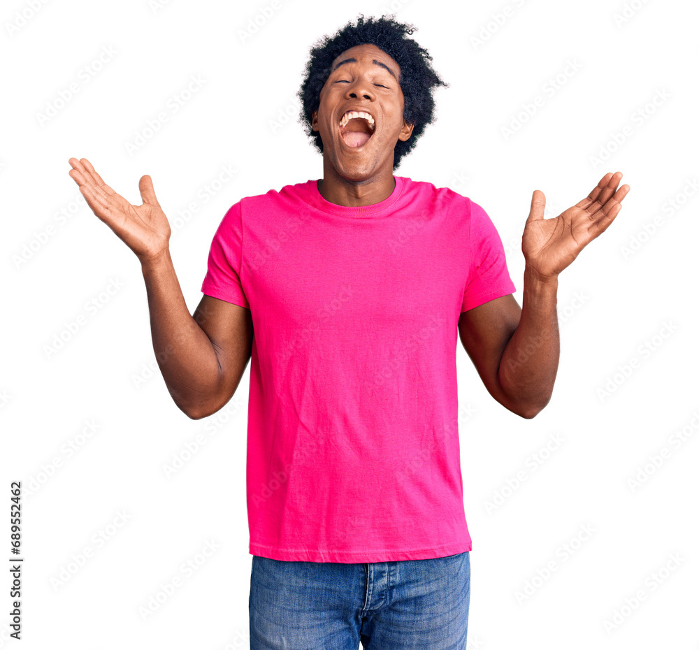 Handsome african american man with afro hair wearing casual pink tshirt celebrating mad and crazy for success with arms raised and closed eyes screaming excited. winner concept Handsome african american man with afro hair wearing casual pink tshirt celebrating mad and crazy for success with arms raised and closed eyes screaming excited. winner concept
