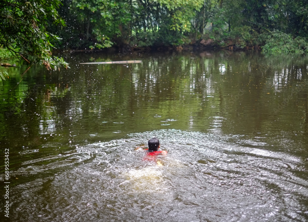 South asian young girl is swimming in a rural pond South asian young girl is swimming in a rural pond