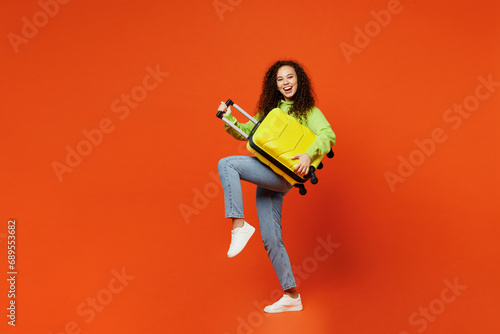 Full body traveler woman in casual clothes hold suitcase bag pov play guitar isolated on plain orange background Tourist travel abroad in free spare time rest getaway Air flight trip journey concept #689553682