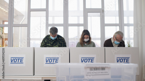 People in protective face masks voting at the polling place during elections amid the pandemic