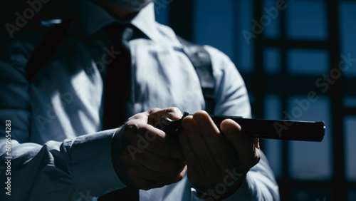 Canvas Print A police detective is charging a weapon in a dark office and aiming it, testing