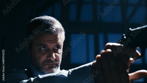 An intelligence officer is drawing a gun, aiming it into the darkness, and testing the weapon photo