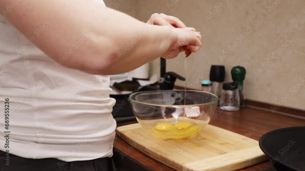 The hands of a woman cracking an eggshell and dropping it into a bowl The hands of a woman cracking an eggshell and dropping it into a bowl