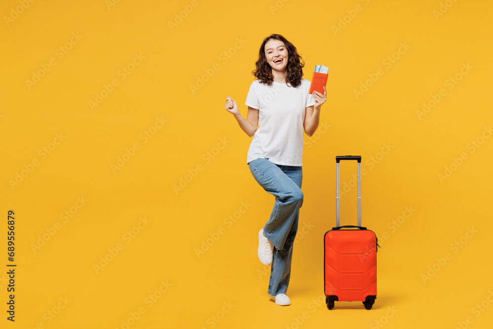 Traveler woman wear t-shirt casual clothes hold passport ticket bag isolated on plain yellow orange background. Tourist travel abroad in free spare time rest getaway. Air flight trip journey concept. Traveler woman wear t-shirt casual clothes hold passport ticket bag isolated on plain yellow orange background. Tourist travel abroad in free spare time rest getaway. Air flight trip journey concept.