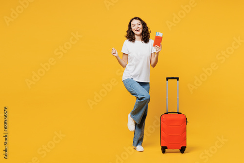 Traveler woman wear t-shirt casual clothes hold passport ticket bag isolated on plain yellow orange background. Tourist travel abroad in free spare time rest getaway. Air flight trip journey concept. photo