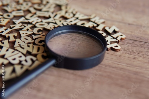 Magnifying glass with scattered alphabet letters on the table. Copy space for text. Education concept.
