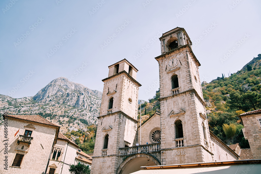 Bell towers of the Cathedral of St. Tryphon among ancient houses at the foot of the mountains. Kotor, Montenegro