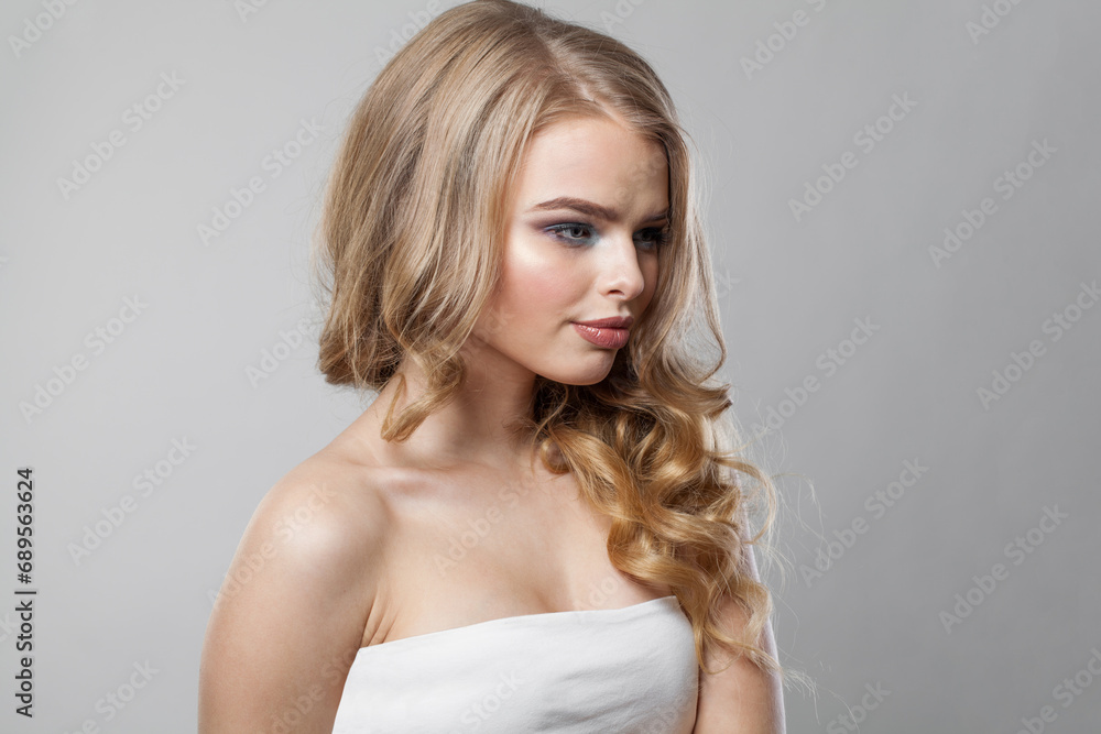 Nice young blonde model with long wavy hair, makeup and clean skin on white background. Healthy woman portrait Nice young blonde model with long wavy hair, makeup and clean skin on white background. Healthy woman portrait