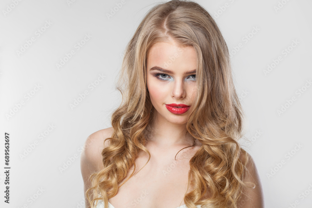 Glorious woman with makeup and long healthy blonde shiny wavy hair posing against white studio wall background. Emotional fashion beauty portrait Glorious woman with makeup and long healthy blonde shiny wavy hair posing against white studio wall background. Emotional fashion beauty portrait