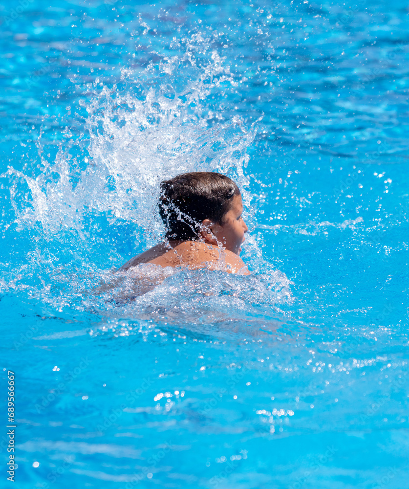 A boy swims in the blue water of a pool