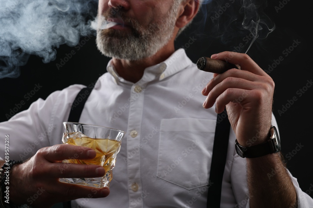 Man with glass of whiskey smoking cigar on black background, closeup Man with glass of whiskey smoking cigar on black background, closeup
