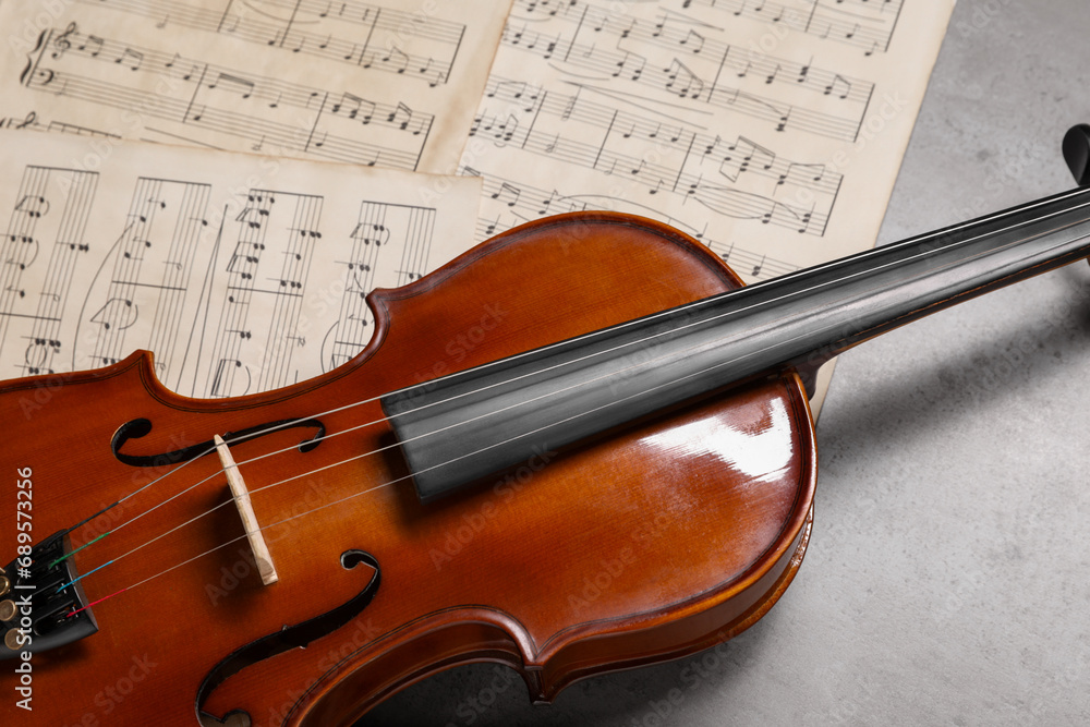 Fototapeta premium Violin and music sheets on grey table, closeup