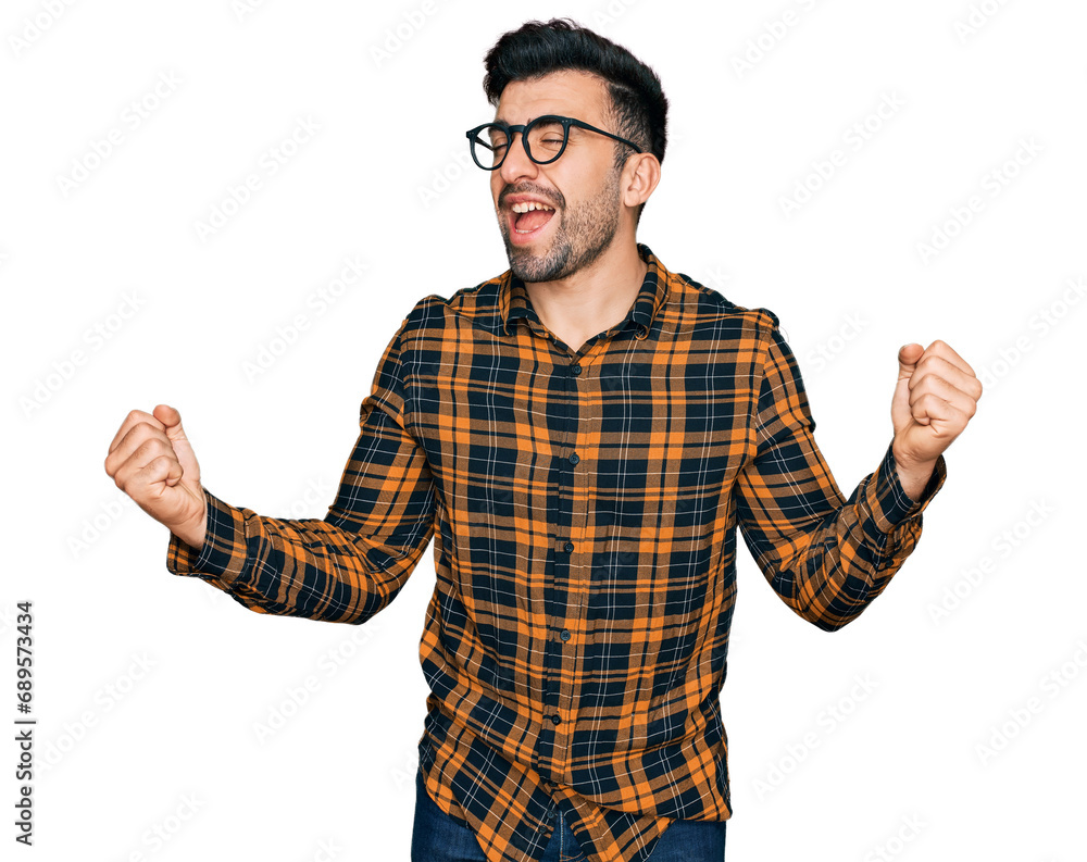 Hispanic man with beard wearing casual clothes and glasses very happy and excited doing winner gesture with arms raised, smiling and screaming for success. celebration concept. Hispanic man with beard wearing casual clothes and glasses very happy and excited doing winner gesture with arms raised, smiling and screaming for success. celebration concept.