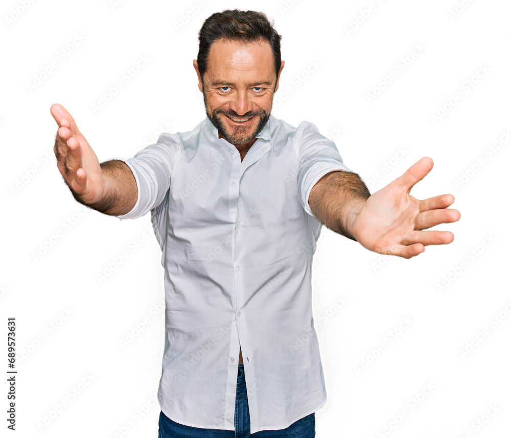 Middle age man wearing casual clothes looking at the camera smiling with open arms for hug. cheerful expression embracing happiness. Middle age man wearing casual clothes looking at the camera smiling with open arms for hug. cheerful expression embracing happiness.
