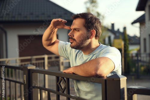 Concept of private life. Curious man spying on neighbours over fence outdoors photo