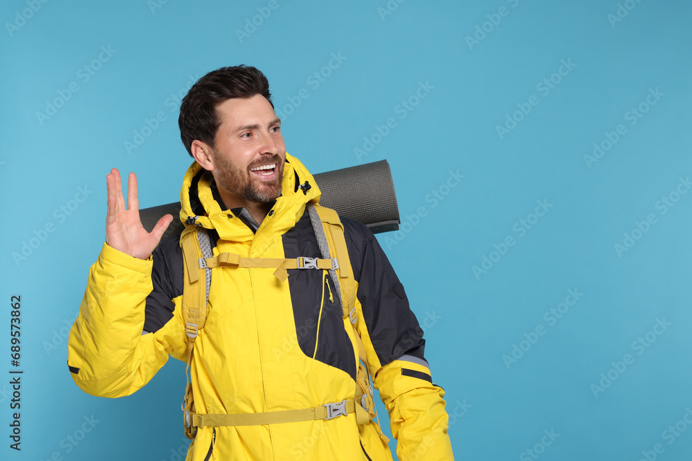 Happy tourist with backpack on light blue background, space for text Happy tourist with backpack on light blue background, space for text