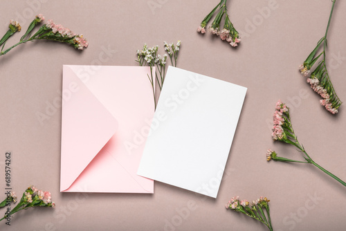 Pink envelope and blank form on a background of flowers. Greeting card, mockup.