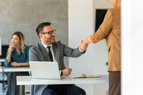 Young business people shaking hands in office. Handshake, finishing successful meeting.