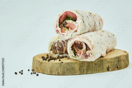 Meat wrapped in a fat mesh lies on a wooden board. Raw product. The dish lyulya is a kebab. White background. photo