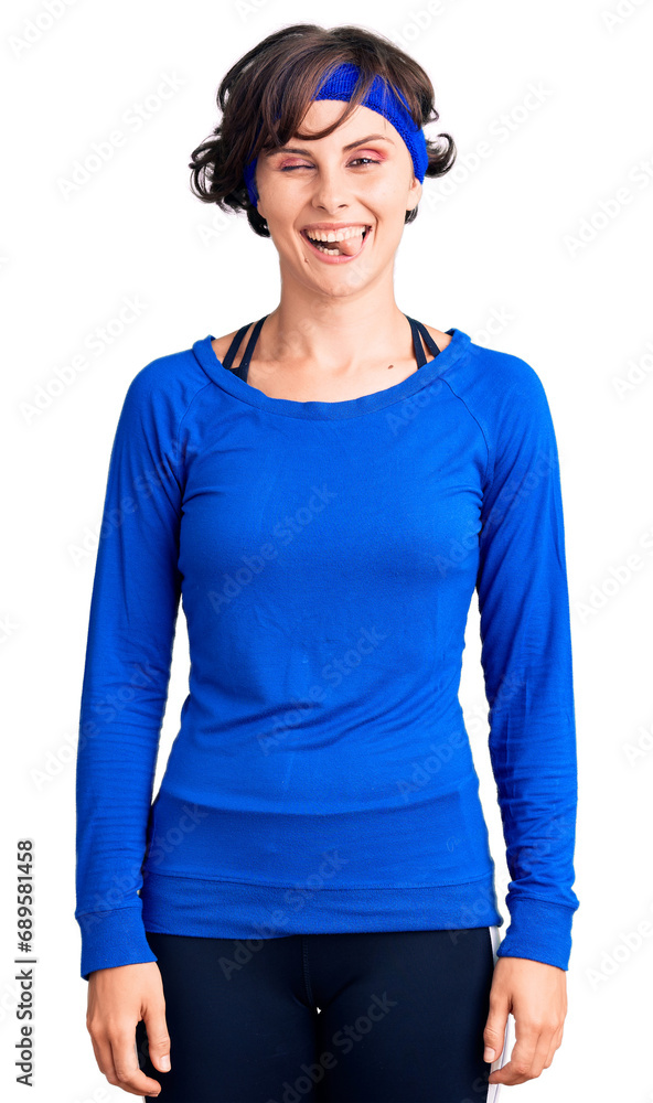 Beautiful young woman with short hair wearing training workout clothes winking looking at the camera with sexy expression, cheerful and happy face. Beautiful young woman with short hair wearing training workout clothes winking looking at the camera with sexy expression, cheerful and happy face.