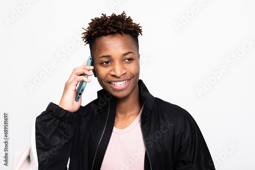 African american dark skinned man with cell phoone over white background in studio isolated smiling loking into distance talking by phone while shooting process.